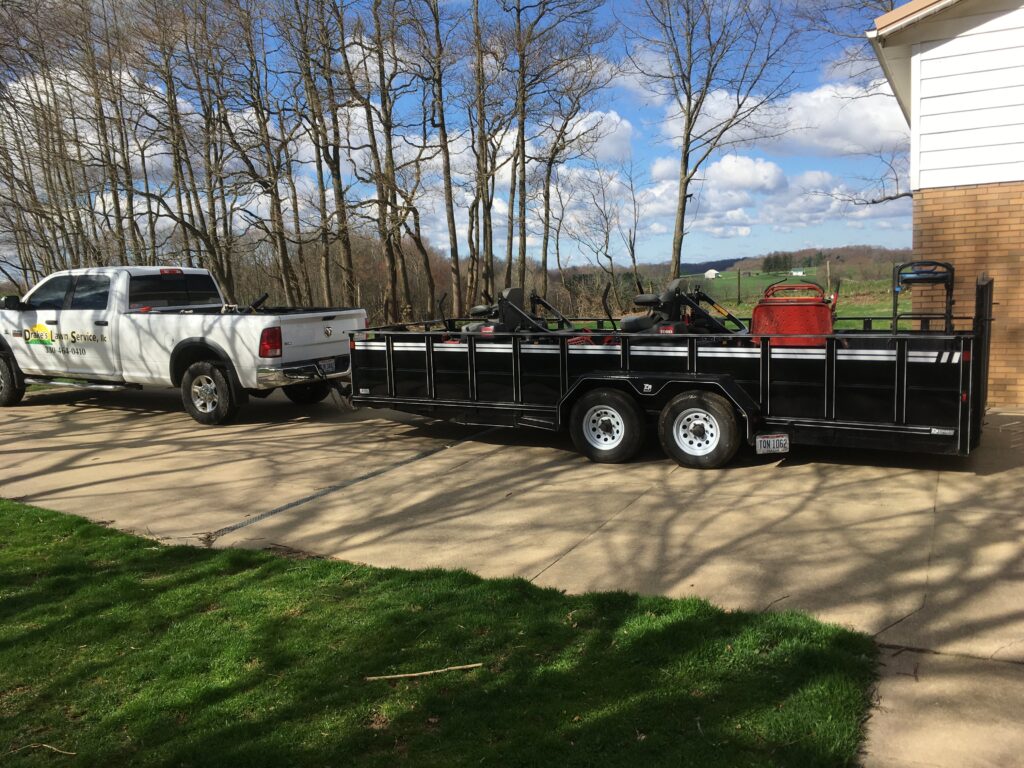 Drake's Lawn Service work truck and trailer carrying lawnmowers.